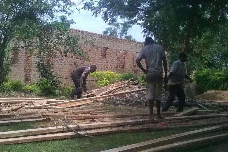 three people handling pieces of wood working to build a library in Uganda. Photo courtesy of Libraries for the World
