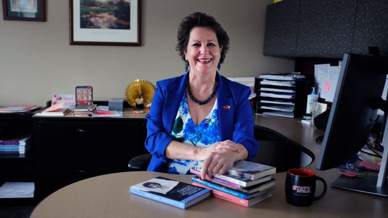 Distinguished Professor Dr. Roberta Seelinger Trites seated at her desk with her books
