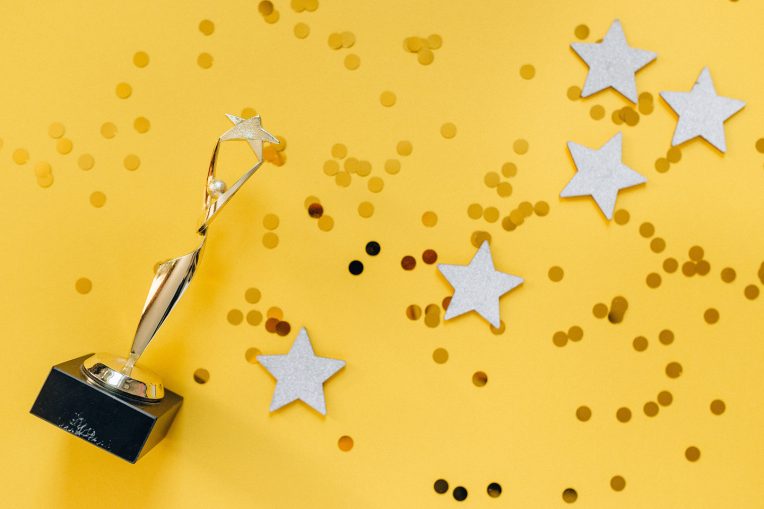 A gold trophy, confetti, and gold stars