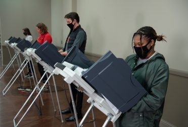 masked voters at distanced voting machines