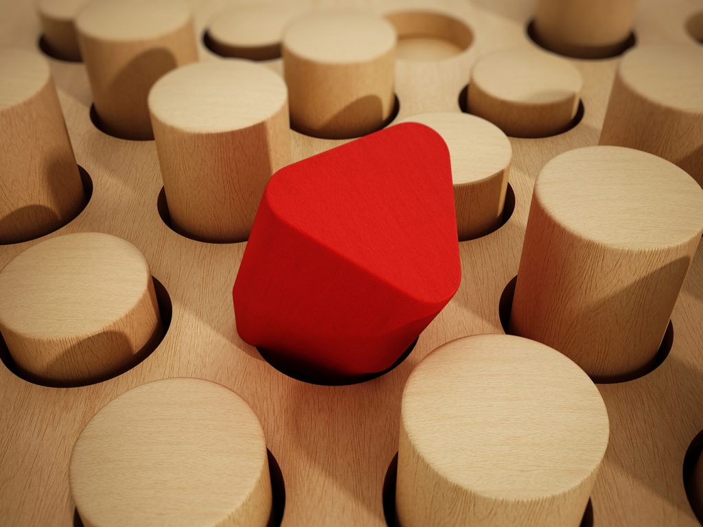 Red prisim woodcute placed in round slot, surrounded by round pegs