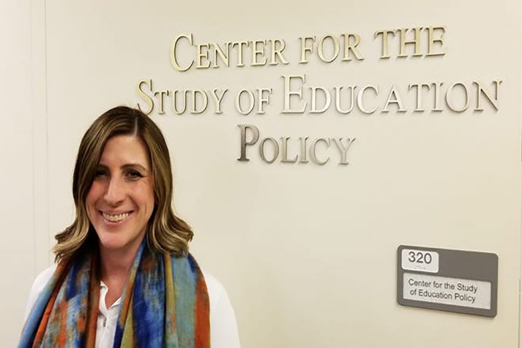 Woman stands in front of a sign that reads "Center For the Study of Education Policy"