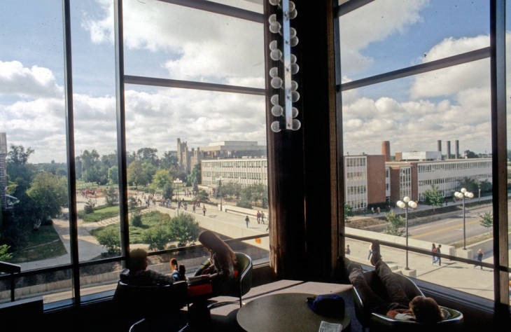 Students studying in corner of Floor 4 with the College Avenue Bridge and Schroeder Hall visible out the windows. Photograph from 1980.