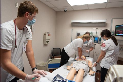 Students work on manikin in MCN's nursing simulation lab.