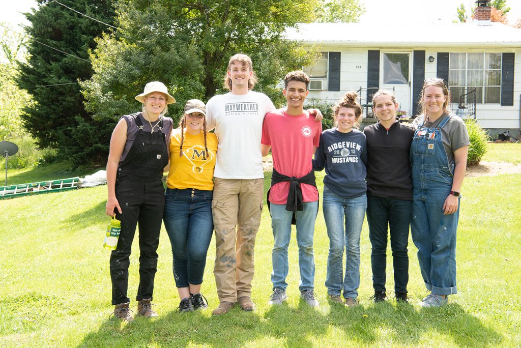 Rose Chelednik (left), of Tri-Cities Home Repair; Anna Raymond; Cameron Perry, liaison; Victor Ventura; Katie Dowling; William Restis; and Caroline Nowak pose for a photo on the last day of service in front of the final house they roofed together.