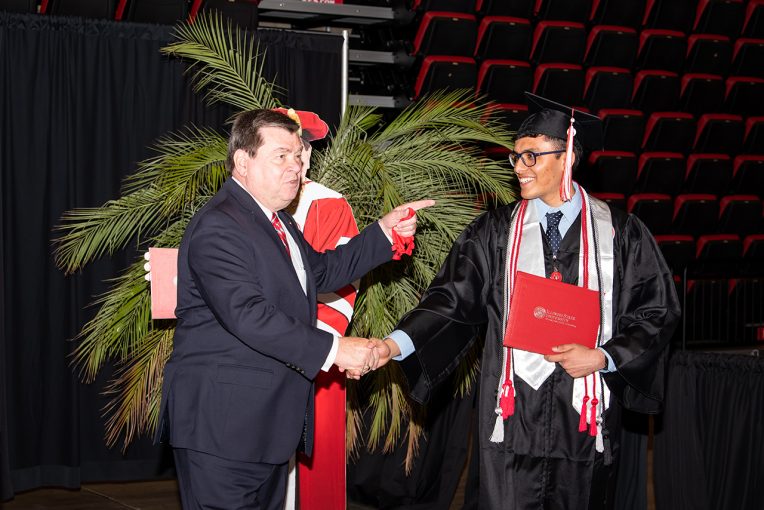 President Dietz shakes hand with a graduate