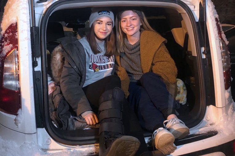 two individuals in the back of a car on a winter night