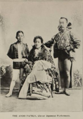 Photo of the Ando family circus performers with a woman sitting in a chair, a child standing to her right, and an adult male standing to her left