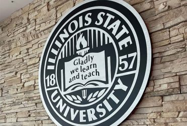 seal of Illinois State University carved in wood wit the words Gladly we learn and teach