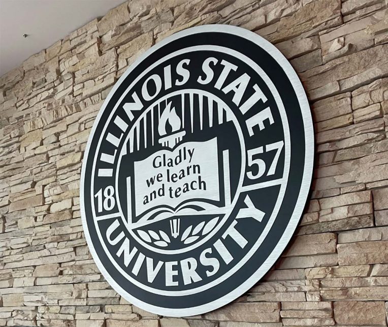 seal of Illinois State University carved in wood wit the words Gladly we learn and teach