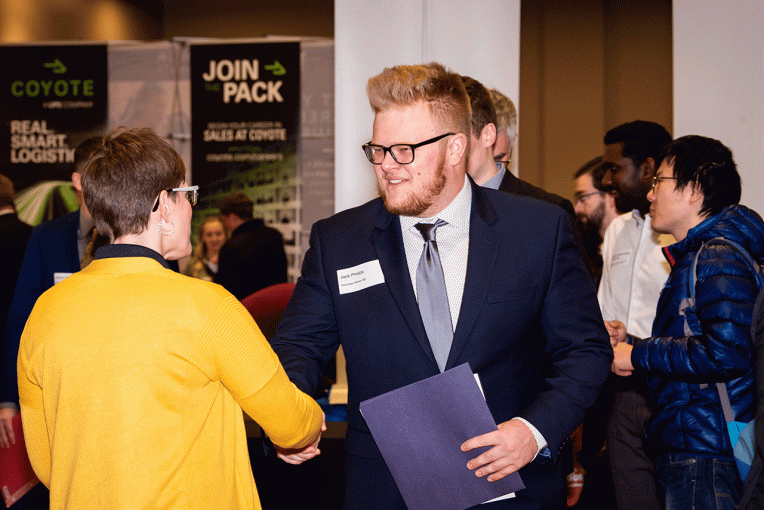 student shakes hands with an employer at a career fair