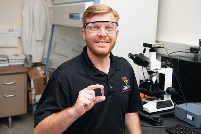 Dr. Jeremy Driskell holds object in lab