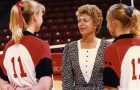 Woman in suit talking to two players in volleyball uniform