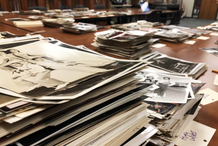 photograph of stacks of photographs sitting on a table in Special Collections' Reading Room