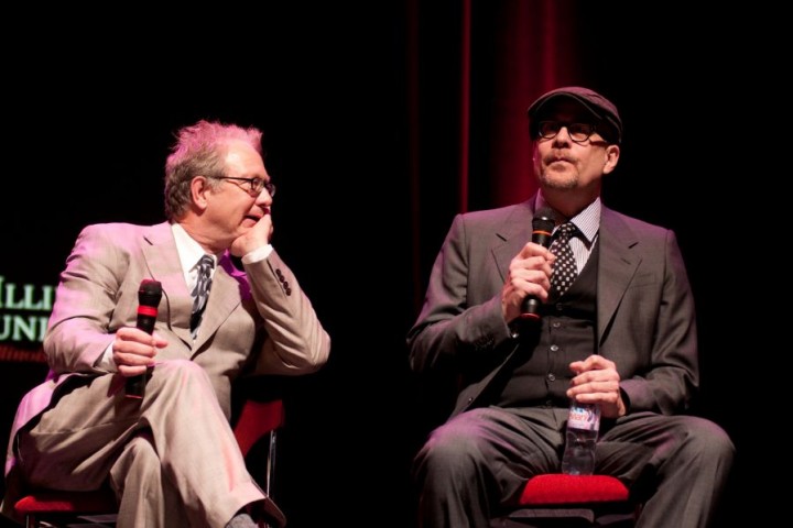 two men seated with microphones