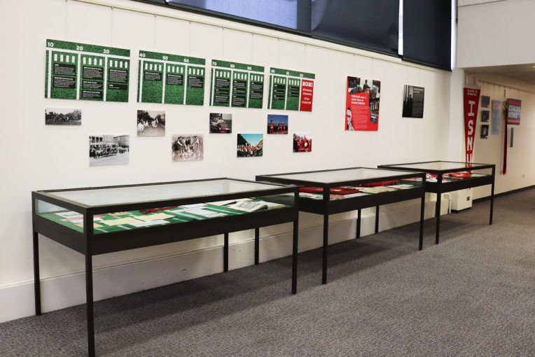 Photograph of display cases and wall mounted items that make up the Coming Home exhibit at Milner Library