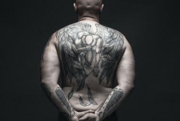 Cover image of Redbird Scholar's fall 2021 issue showing man's back and lower arms covered with tattoos