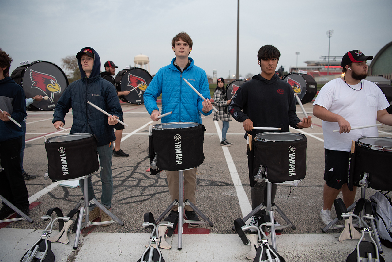 Morr stands drumming between four students, two on each side.