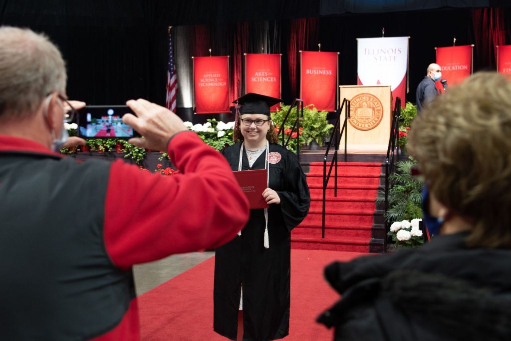 Family members take photos of a student in cap and gown during last year's Redbird Stage Crossing