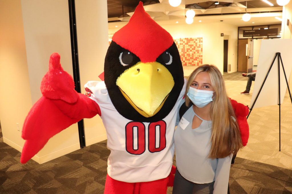 Student posing for a picture with Reggie Redbird.