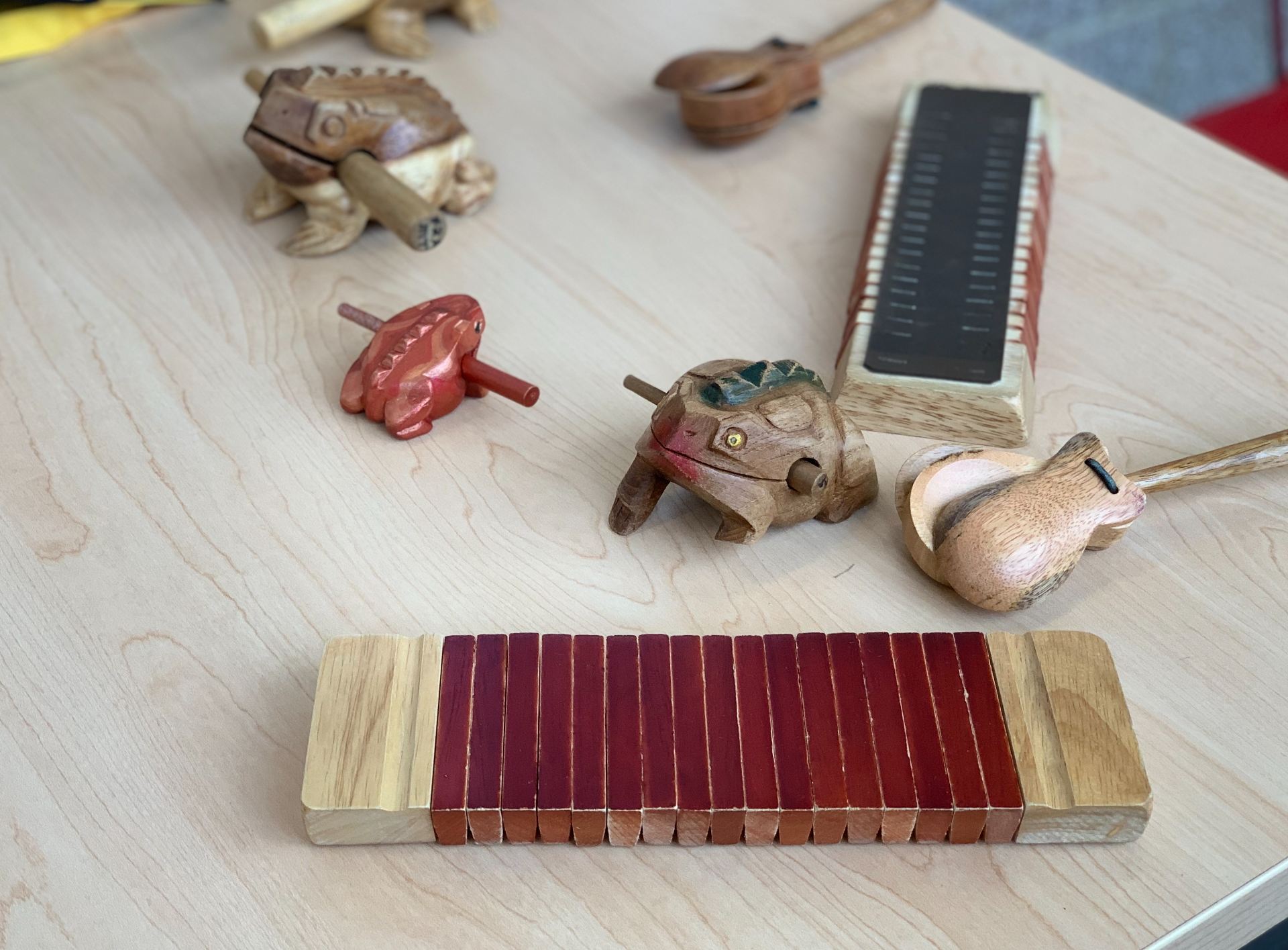 Three types of wooden noisemakers (castanets, frog guiros, and clackers) laid out on a table.