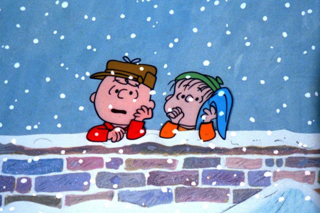 Cartoon still of Charlie Brown and Linus leaning on a snow-covered wall