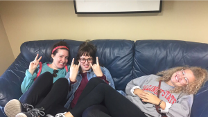 Three students laughing on a couch.