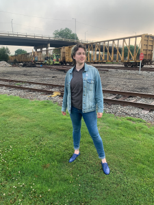 Person posing near train tracks.