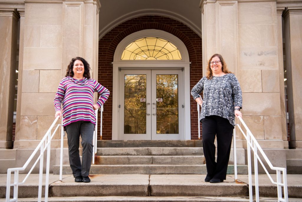 two women posed outside campus building