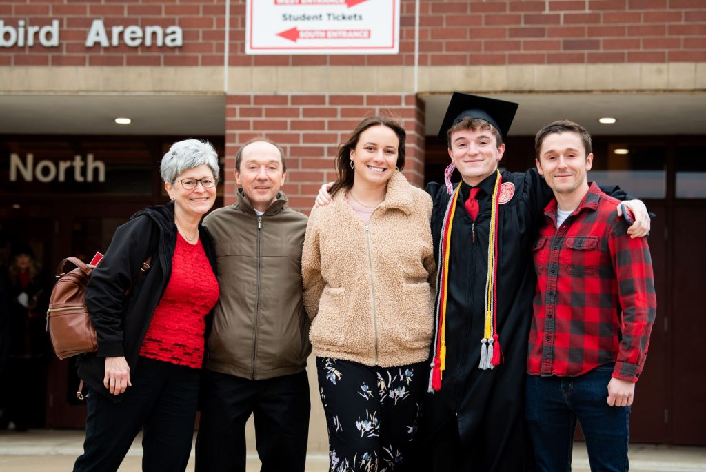 A graduate poses with their family after commencement.