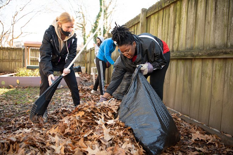 Senior Shaniece Cole, right, and sophomore Nikki Zavondy, left, work to rake and bag leaves from the playgrounds at Hope House.