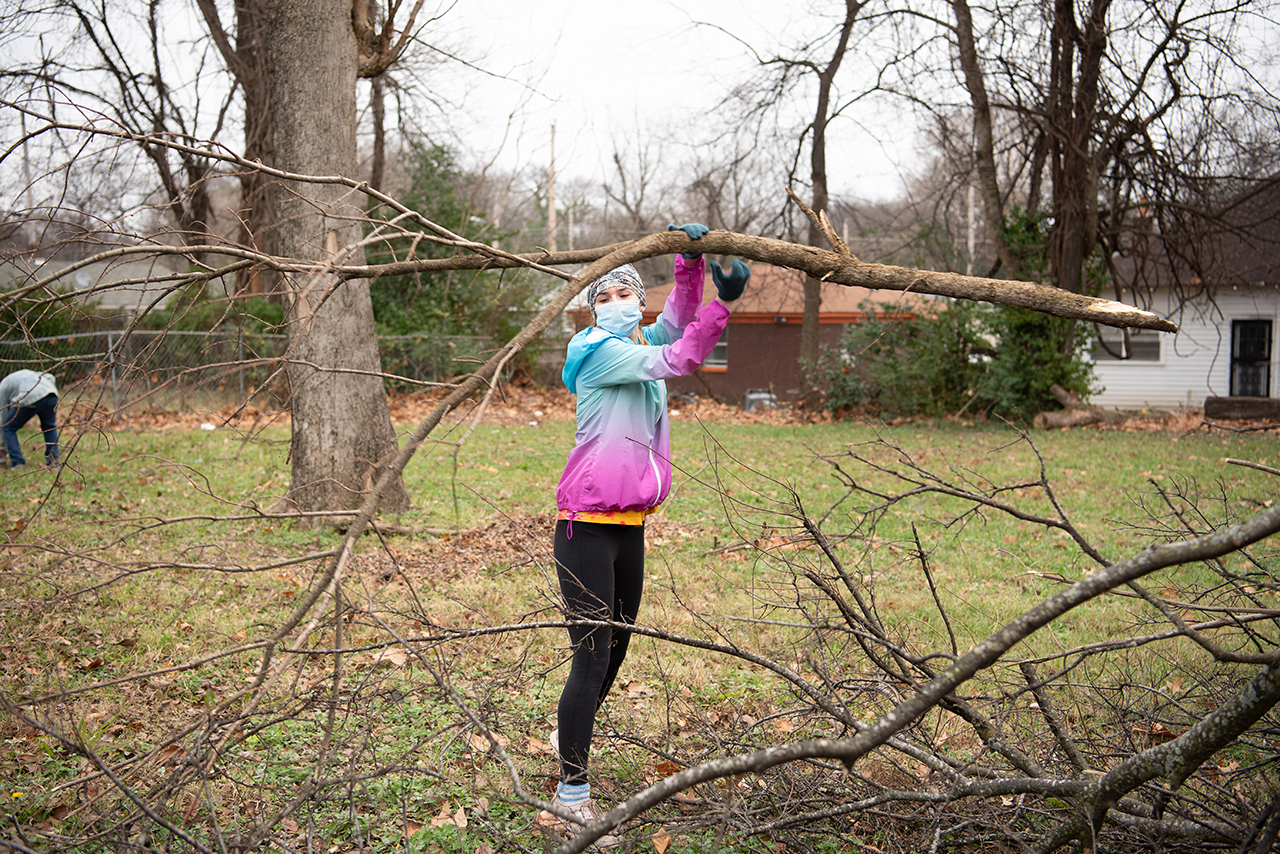 Rylie Linn tosses a branch into a brush pile after removing it from the property of a newly renovated home near Jacob’s Ladder.
