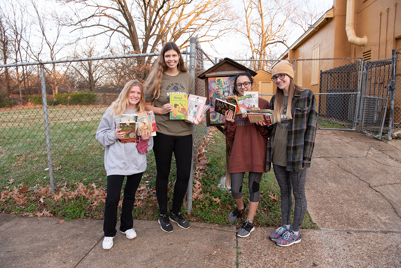 Nikki Navodny, Nicole Martin, Joie Pecoraro, and Rylie Linn hold up the books they bought at a local thrift store to stock a little library near Jacob’s Ladder.