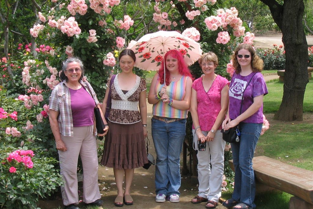 Women smiling standing in front of a flower arch
