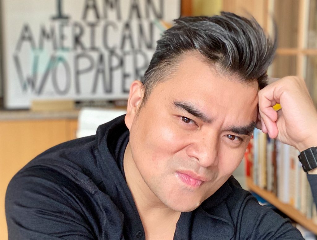 headshotr of Jose Antonio Vargas with blurred words in the background that say I am an American without papers