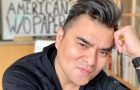headshotr of Jose Antonio Vargas with blurred words in the background that say I am an American without papers