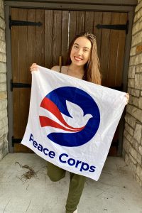 Peyton Metry stands with Peace Corps flag.