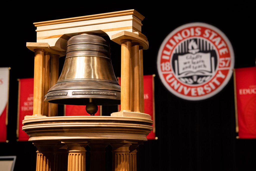 bell on a stage with the Illinois State University seal in the background