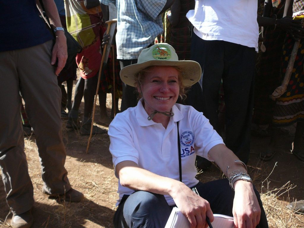 Woman sitting on the ground in hat smiling