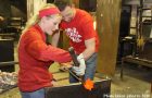 man and woman work on glassblowing piece