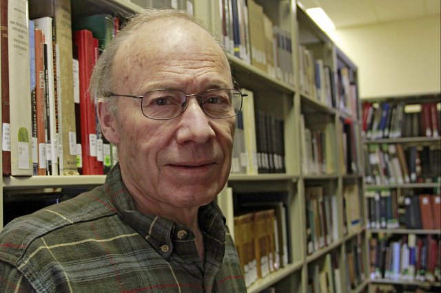 Distinguished Professor Emeritus of History Mark Wyman standing in front of shelves of books