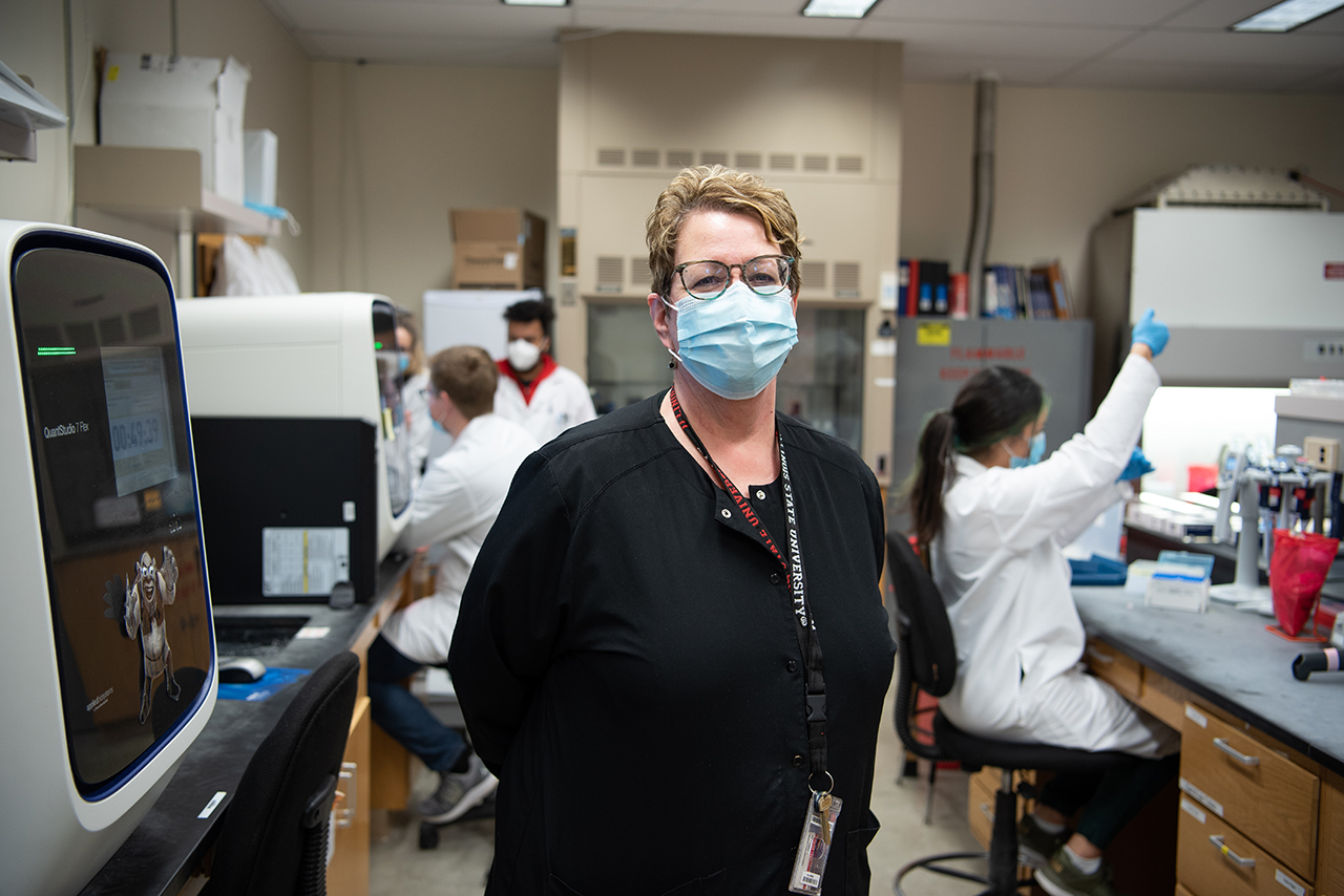 woman standing in a lab wearing a mask