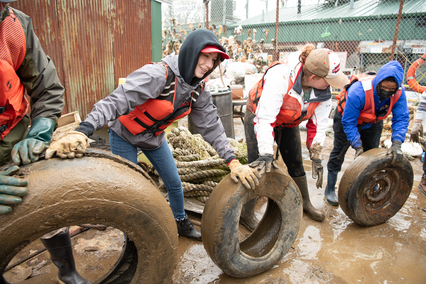 From left, trip leader Cassidy Devine, a freshman management major, Annellia Pierce, a senior philosophy major, and Kaylan Boyd-Harris, a creative technologies graduate student, pass tires down the line as the group works to move over 250 tires from one barge to the other.