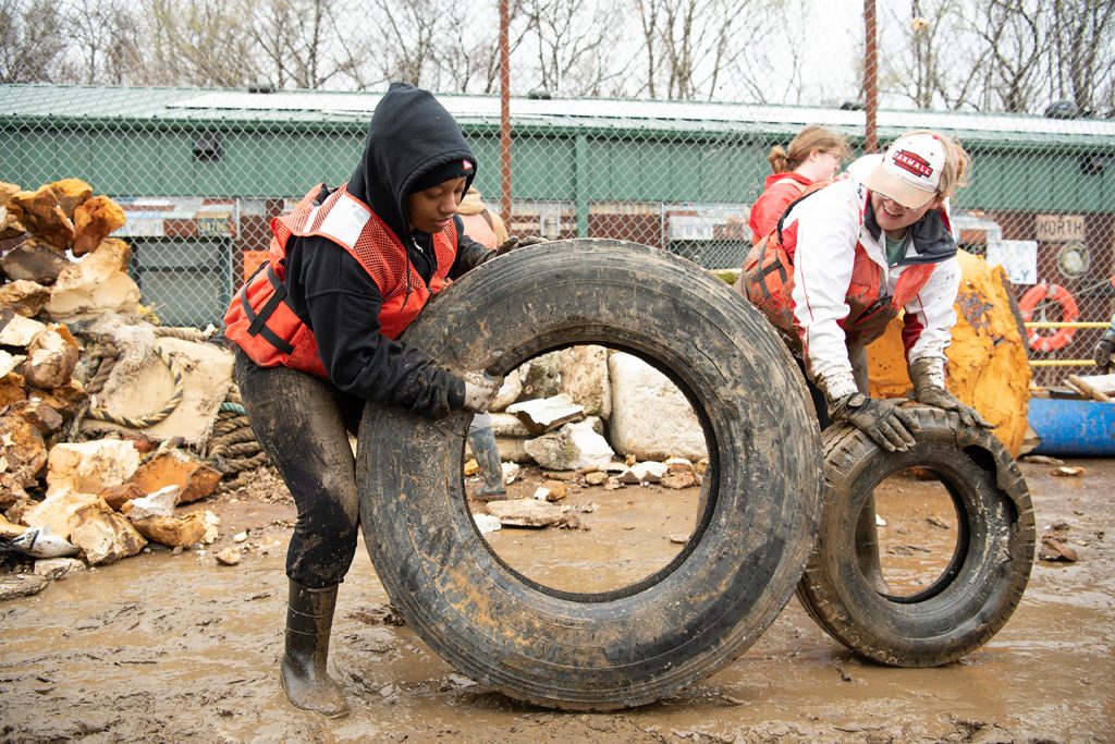 Junior Dareya Ellis, left, and senior philosophy major Annellia Pierce roll tires along the barge as they work to clean up McKellar Lake in Memphis with Living Lands & Waters.
