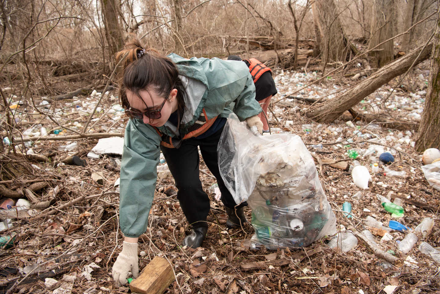 Junior social work major Klaudia Krei picks up plastics along the shoreline of McKellar Lake.