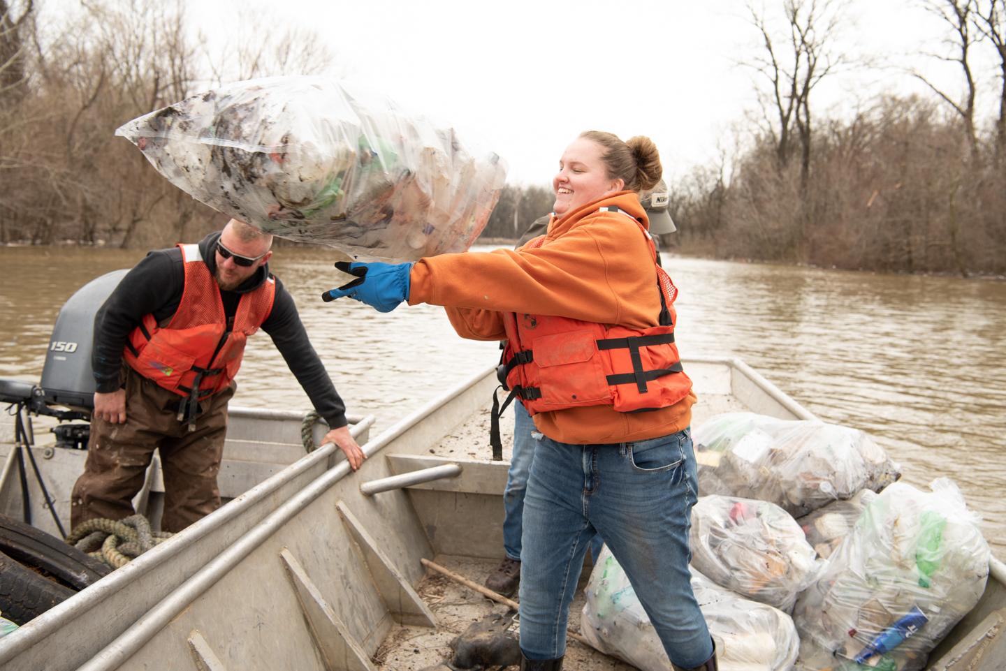 Junior social work major Sarah Kraft tosses a bag or recyclables onto the garbage boat.