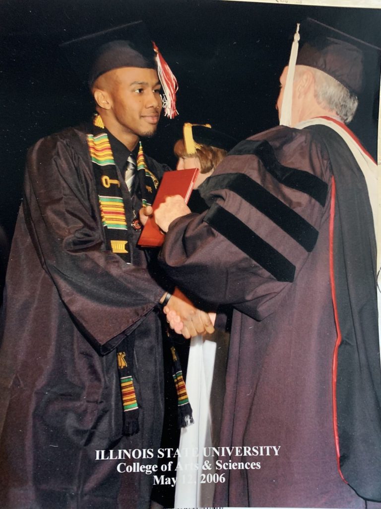 A man handing another man his degree