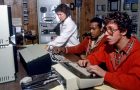 Photograph of three student operators monitor equipment in the TV-10 control room, December 1980