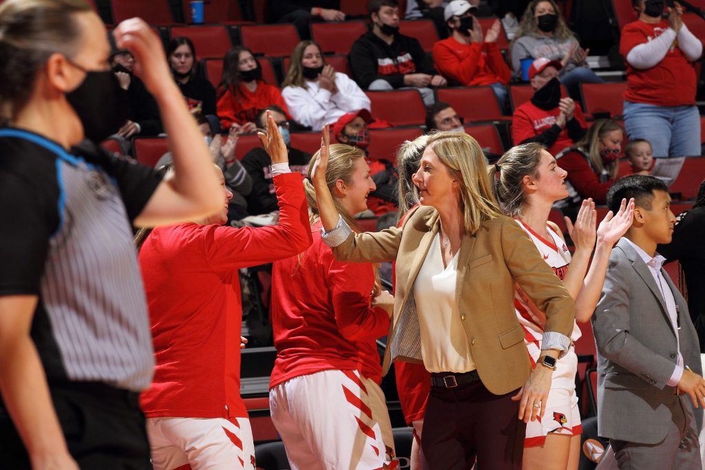 women's basketball coaches and players high-five on the bench
