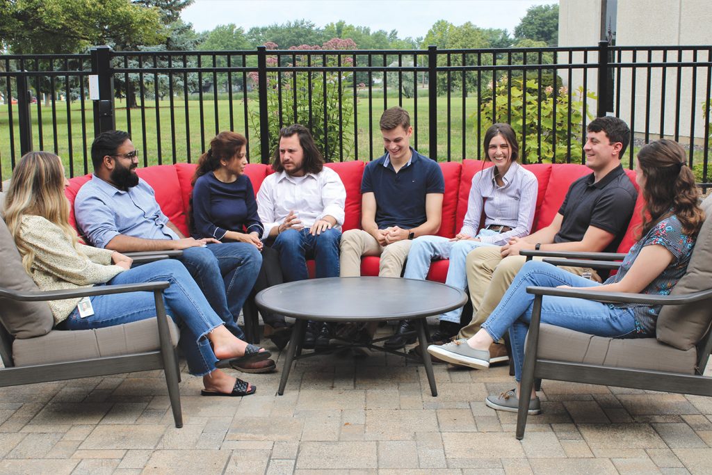 A group of people sitting down on chairs outdoors.
